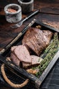 Grilled Tri Tip steak, sirloin bottom beef in a tray with herbs. Wooden background. Top view