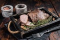Grilled Tri Tip steak, sirloin bottom beef in a tray with herbs. Wooden background. Top view