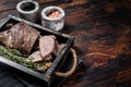 Grilled Tri Tip steak, sirloin bottom beef in a tray with herbs. Wooden background. Top view. Copy space