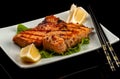 Grilled trout with lemon on a platter on a black table