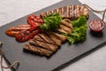 Homemade grilled turkey breast sliced steaks with baked peppers, lettuce and tomato on a black board. Horizontal Royalty Free Stock Photo