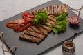 Homemade grilled turkey breast sliced steaks with baked peppers,lettuce and tomato on a black board. Next to the pepper Royalty Free Stock Photo