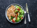 Grilled turkey chops and tomatoes, cucumbers, greens salad on a dark background, top. Healthy food diet concept Royalty Free Stock Photo