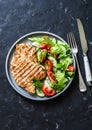 Grilled turkey chops and tomatoes, cucumbers, greens salad on a dark background, top. Healthy food diet concept Royalty Free Stock Photo