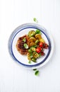 Grilled turkey steak with vegetables and fresh basil leaves on a plate