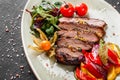 Grilled veal steak with salad and vegetables in plate on dark stone background. Hot Meat Dishes, top view Royalty Free Stock Photo