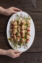 Grilled vegetable and chicken skewers with bell peppers, zucchini, onion and mushrooms on a wooden table in female hands, top view Royalty Free Stock Photo