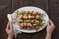 Grilled vegetable and chicken skewers with bell peppers, zucchini, onion and mushrooms on a wooden table in female hands, top view Royalty Free Stock Photo