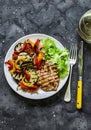 Grilled vegetables, chicken breast and a glass of white wine - delicious healthy diet lunch on a dark background, top view Royalty Free Stock Photo