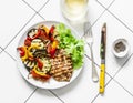 Grilled vegetables, chicken breast and a glass of white wine - delicious healthy diet lunch on a light background, top view Royalty Free Stock Photo