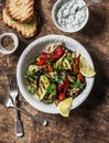 Grilled vegetables eggplant, zucchini, pepper and tzadziki sauce on a wooden background, top view