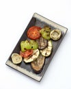 Grilled vegetables on platter. Clay plate with fried zucchini, eggplant, bell pepper, tomato and onion isolated on white Royalty Free Stock Photo