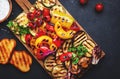 Grilled vegetables on rustic wooden cutting board,: colorful paprika, zucchini, eggplant, mushrooms, tomatoes and red onions with Royalty Free Stock Photo