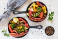 Grilled vegetables and smokies in fry pans.