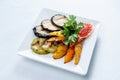 Grilled vegetables on white square plate.