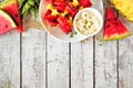 Grilled summer watermelon and pineapple fruit kabobs, overhead view top border on white wood