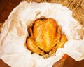 grilled whole chicken with crispy Golden skin on white parchment, top view, close-up