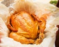 grilled whole chicken with crispy Golden skin on white parchment, top view, close-up