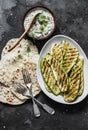 Grilled zucchini, tortillas and tzadziki sauce - delicious greek style snack, tapas on a dark background, top view