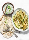 Grilled zucchini, tortillas and tzadziki sauce - delicious greek style snack, tapas on a light background, top view