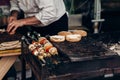 grilling barbecue kebab on skewers. meat and vegetables and bread buns roasting on grill. man roasting meat. chef in form cooking Royalty Free Stock Photo