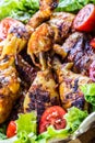 Grilling. Grilled chicken. Grilled chicken legs. Grilled chicken legs, lettuce and cherry tomatoes. Traditional cuisine. Royalty Free Stock Photo