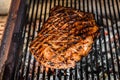 Grilling marinated angus beef flank steak on hot coals barbecue grill Royalty Free Stock Photo
