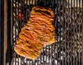 Grilling marinated beef flank steak on hot coals barbecue grill