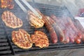 Grilling sausages, burgers, pork steak on barbecues gas grill for party. Hot dogs,sausages and hamburgers on a barbeque, bbq. Smok Royalty Free Stock Photo