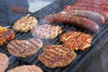 Grilling sausages, burgers, pork steak on barbecues gas grill for party. Hot dogs,sausages and hamburgers on a barbeque, bbq. Smok Royalty Free Stock Photo
