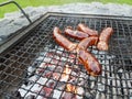 Grilling sausages on the grill. Frying food on charcoal and on fire. Fatty food. Calories and energy for muscles. Picnic on the st Royalty Free Stock Photo