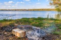 Grilling sausages in portable barbecue grill on campfire at riverbank Royalty Free Stock Photo