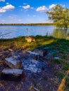 Grilling sausages in portable barbecue grill on campfire at riverbank Royalty Free Stock Photo