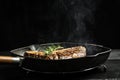 Grilling a tasty tender marinated t-bone steak seasoned with fresh rosemary on frying grill pan on black. wagyu porterhouse Royalty Free Stock Photo