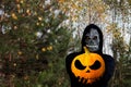 Close-up portrait of grim reaper. Man in death mask with fire flame in eyes on pine yellow tree forest background Royalty Free Stock Photo