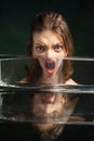 Modern art photography. Funny weird girl& x27;s face through glass of water. Object distortion, optical illusion