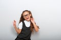 Grimacing pupil girl with long hair style in fashion eyeglasses in uniform dancing