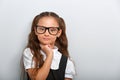 Grimacing pupil girl with long hair style in fashion eyeglasses in uniform thinking about holidays and looking serious. Closeup