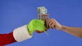 The Grinchs green haired hand hold a Christmas sock with dollar bills and a mans hand takes it away. Gift Royalty Free Stock Photo