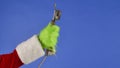 The Grinchs green haired hand holds an antique telephone receiver on a blue isolated background. Gift Snatcher Royalty Free Stock Photo