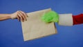 The Grinchs green haired hand reaches out and a mans hand takes a paper bag on an isolated blue background Royalty Free Stock Photo