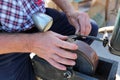 Grinder with grindstone grinding the blade of billhook Royalty Free Stock Photo