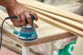 Grinder worker polishes a wooden board. Sanding boards Orbital eccentric machine. Royalty Free Stock Photo