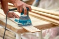 Grinder worker polishes a wooden board. Sanding boards Orbital eccentric machine. Royalty Free Stock Photo