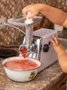 Grinding tomatoes through a meat grinder Royalty Free Stock Photo