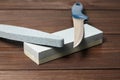 Grindstones. Two whetstones and steel knife blade. Oval and rectangular double layer sharpening stone on wooden table background