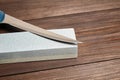 Grindstones. Two whetstones and steel knife blade. Oval and rectangular double layer sharpening stone on wooden table Royalty Free Stock Photo