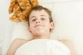 Grinning boy in bed covered with blanket