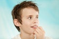 Grinning boy with messy hair and hand near mouth Royalty Free Stock Photo