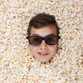 Grinning, flaunt young boy in stereo glasses looking out of popcorn Royalty Free Stock Photo